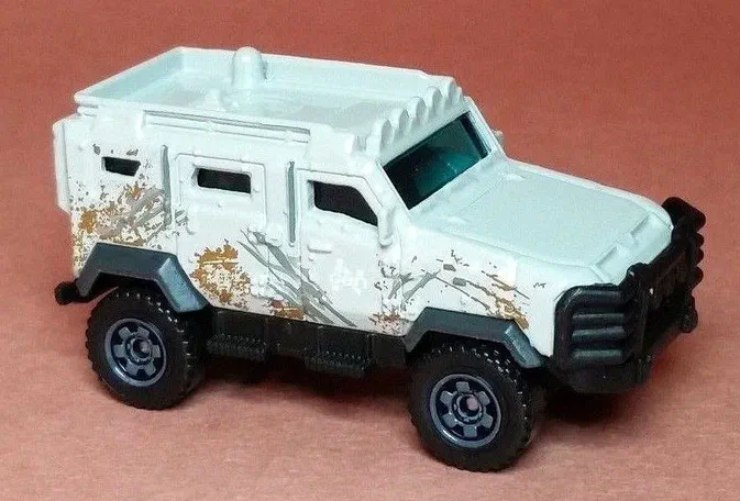 Petit camion Matchbox Textron Tiger blanc avec des traces de boue et d'écraies gris simulées sur le côté.