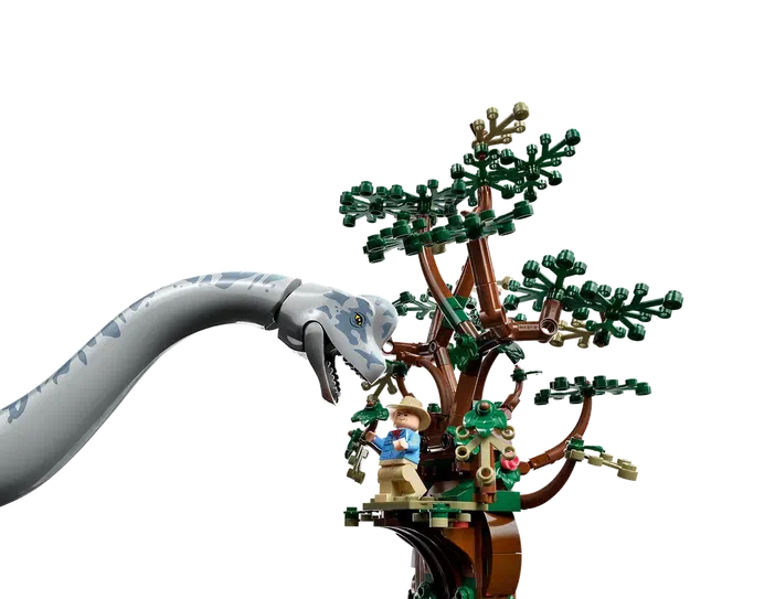 Un dinosaure à long cou en LEGO s'approche d'un arbre où se tient un personnage de la série Jurassic World.