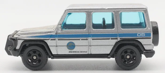 Un jouet Matchbox de type SUV argenté avec des fenêtres bleues et une inscription 'FOR OFFICIAL USE ONLY' sur le côté.
