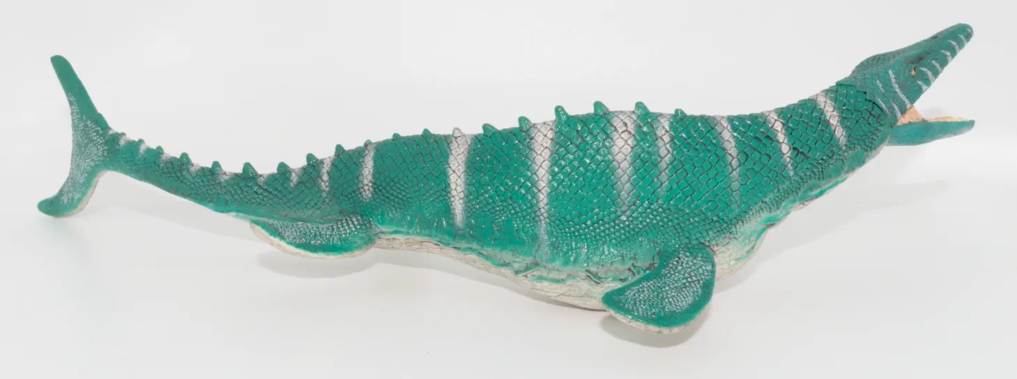 Modèle de dinosaure vert à rayures blanches sur fond blanc.