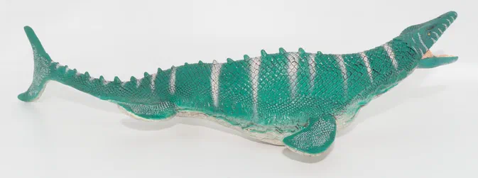 Modèle de dinosaure vert à rayures blanches sur fond blanc.