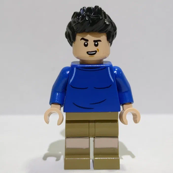 Minifigurine LEGO Kenji avec des cheveux noirs bouclés et un haut bleu.