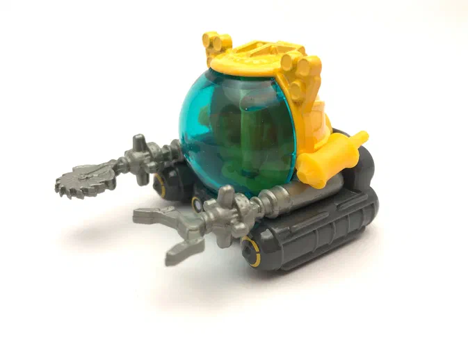 Un sous-marin jouet Matchbox de la série Jurassic World avec une coque transparente bleue et des chenilles grises.
